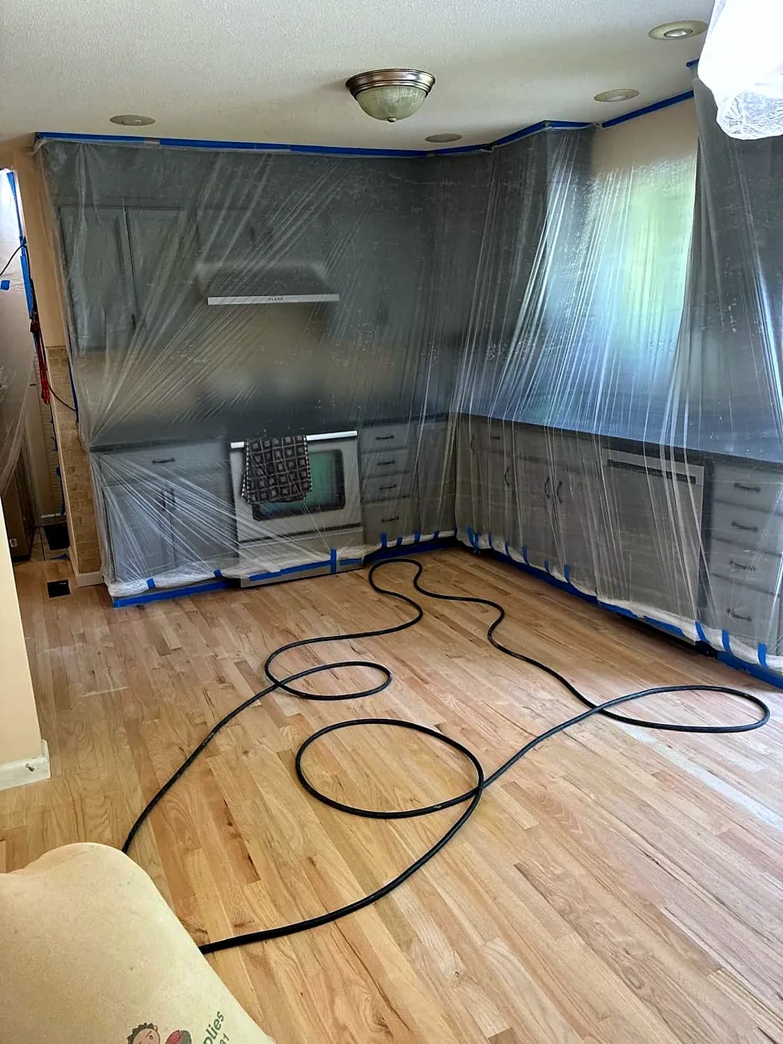 Kitchen cabinets and counters sealed in protective plastic sheeting during a hardwood floor job in Fairfield County, CT