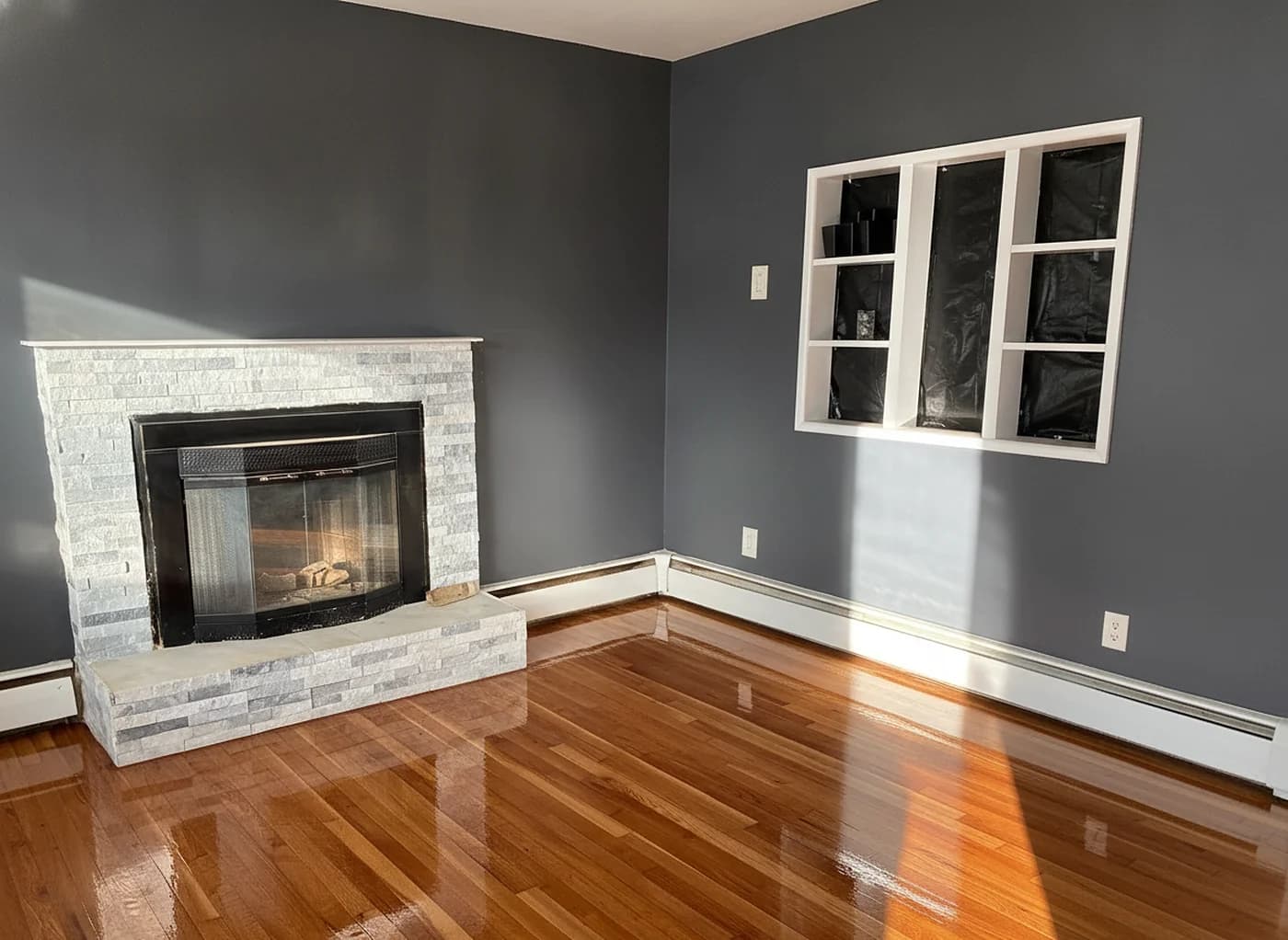 Glossy refinished hardwood living room floor beside a stone fireplace in Fairfield County, CT