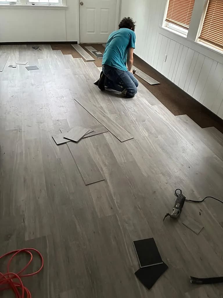Marlon on his knees fitting a new floor by hand