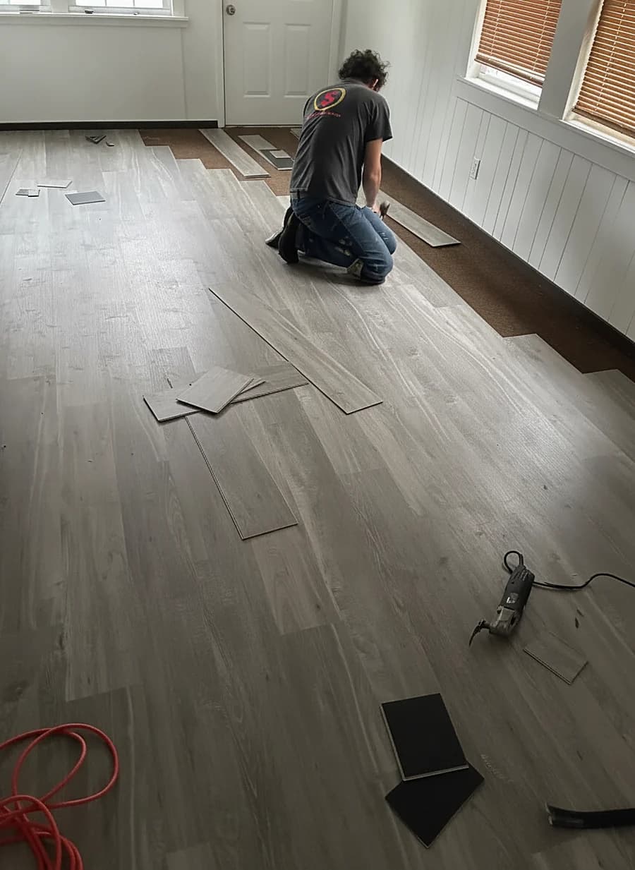 Marlon on his knees fitting a new floor by hand